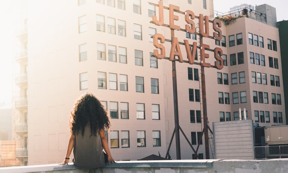 woman in gray top sitting on a building's edge